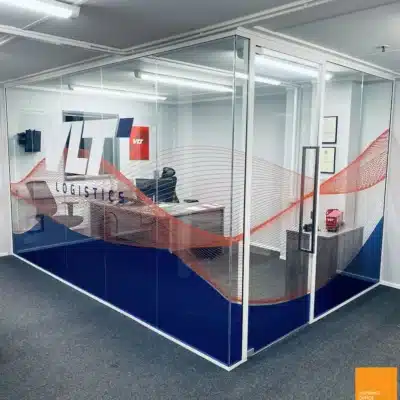 Glass office partition with branded VLT Logistics graphic enclosing a private office