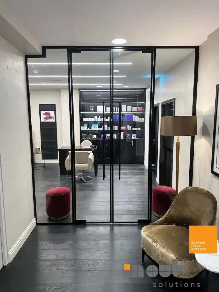 Frameless single glass partition doors opening onto a salon retail and treatment area.