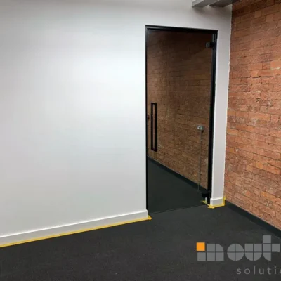 Black glass office door in exposed-brick corridor of Manchester commercial building