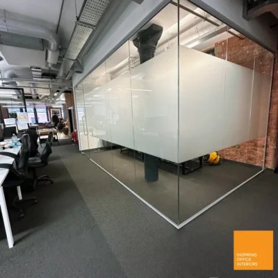 Frosted glass partition wall dividing an exposed-brick office workspace in Manchester