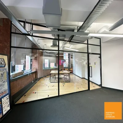 Black-framed glass office partition creating a meeting room in Manchester open-plan workspace