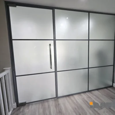Frosted glass home divider with black grid frame separating a hallway from a room in Yorkshire