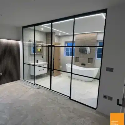 Black-framed interior glass doors leading to a bathroom with freestanding bath in Birmingham home