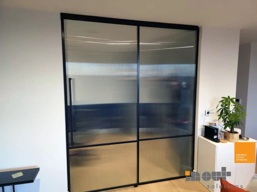 Black-framed fluted glass sliding door used as a room divider in London office.