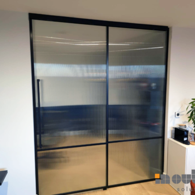 Black-framed fluted glass sliding door used as a room divider in London office.