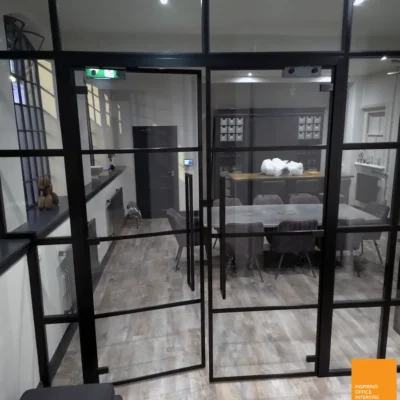 Black-framed glass partition separating a kitchen area from meeting space in Birmingham office
