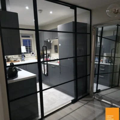 Aluminium-framed glazed room divider with sliding panel separating Bradford kitchen and dining space