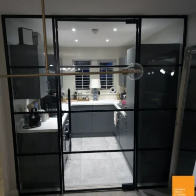Aluminium-framed glazed room divider with open door leading into a Bradford kitchen