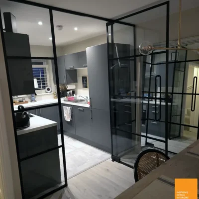 Aluminium-framed glazed room divider separating a Bradford kitchen from dining area with pendant light
