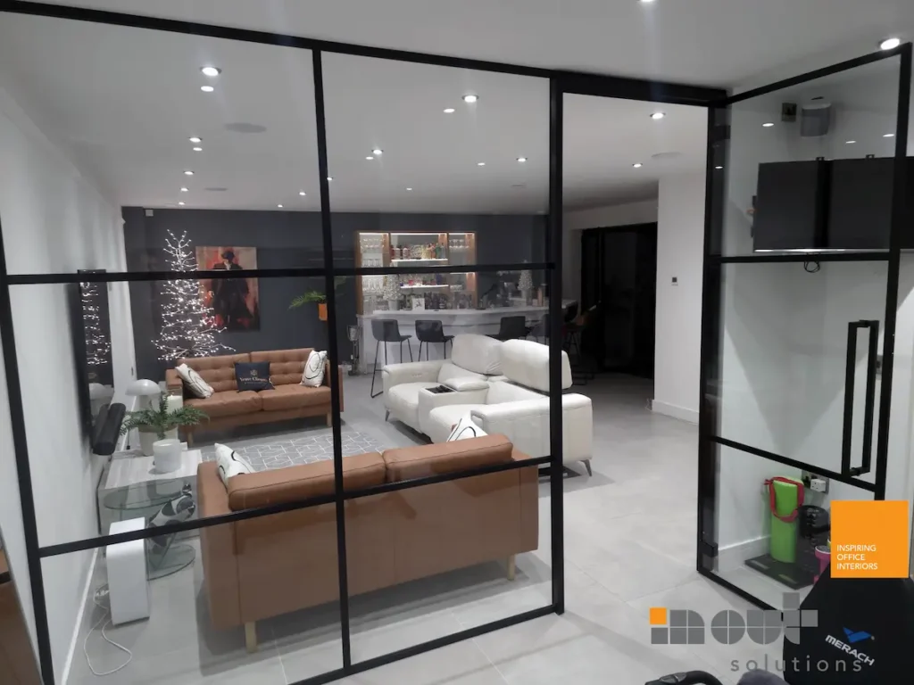 Black-framed glass room divider separating a home bar and lounge area in a Leicestershire property
