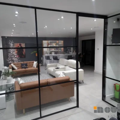 Black-framed glass room divider separating a home bar and lounge area in a Leicestershire property